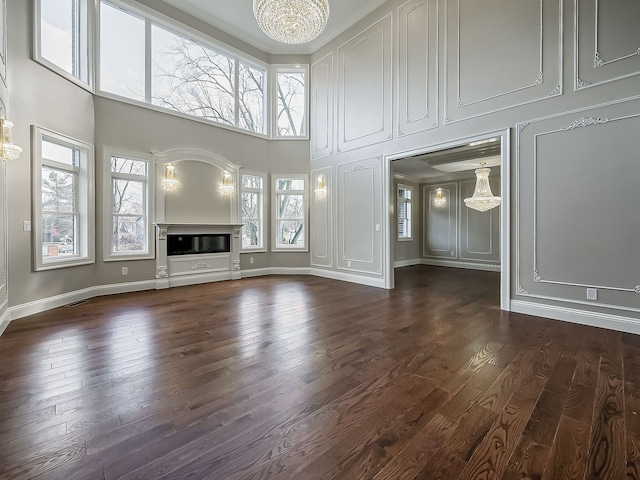 unfurnished living room featuring a towering ceiling, dark hardwood / wood-style floors, and a notable chandelier