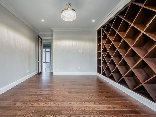 wine room featuring dark hardwood / wood-style flooring, crown molding, and a chandelier