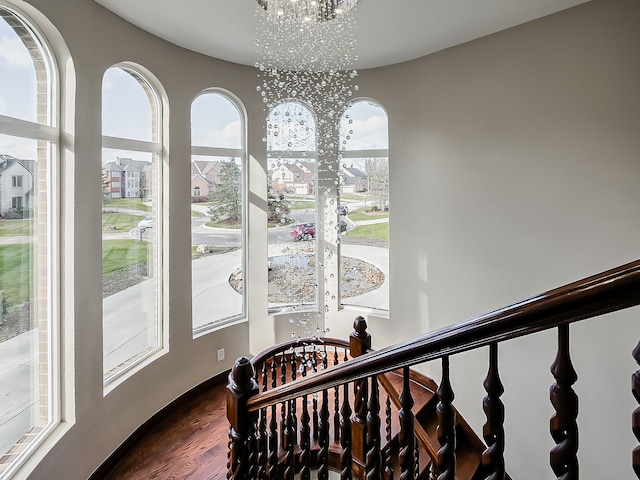 stairway with wood-type flooring and a chandelier