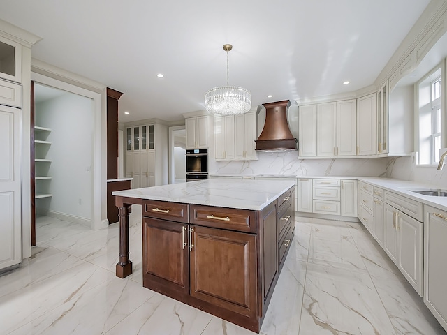 kitchen featuring dark brown cabinetry, hanging light fixtures, a chandelier, a kitchen island, and custom range hood