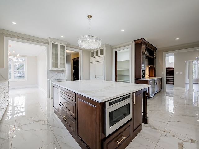 kitchen featuring dark brown cabinetry, white cabinetry, hanging light fixtures, tasteful backsplash, and built in appliances