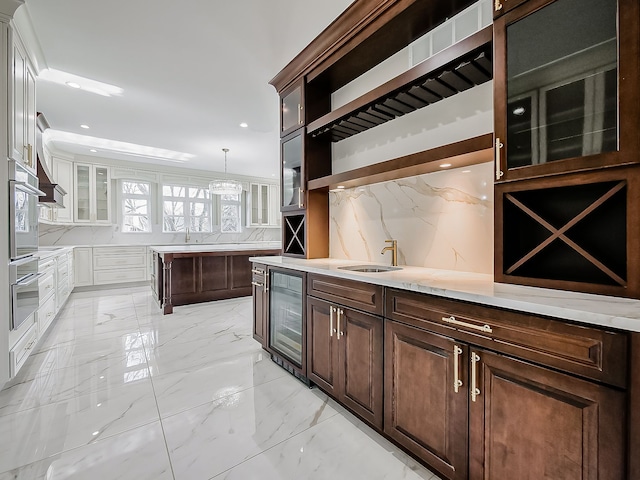 kitchen featuring wine cooler, tasteful backsplash, dark brown cabinetry, sink, and white cabinetry