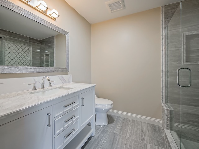 bathroom with vanity, a shower with shower door, and toilet