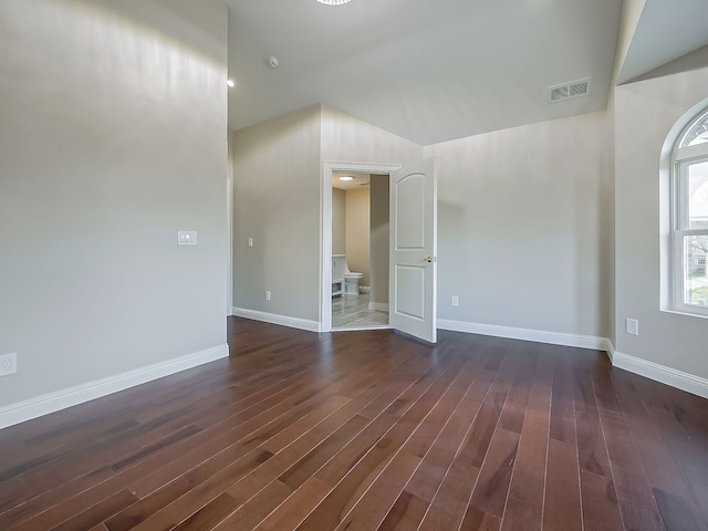 unfurnished room featuring dark wood-type flooring and lofted ceiling