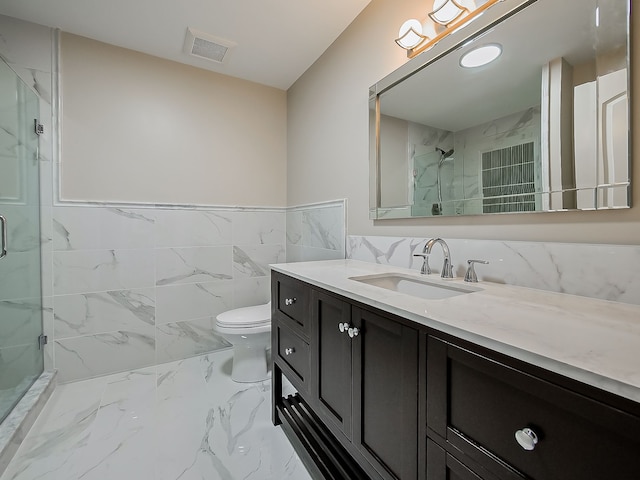 bathroom with vanity, toilet, tile walls, and a shower with shower door