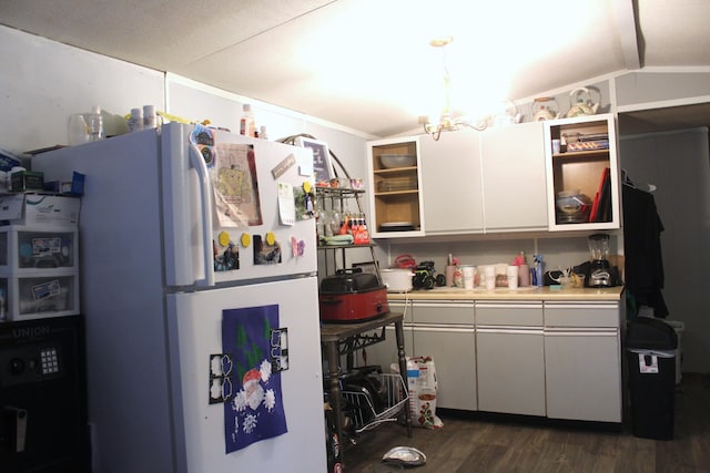 kitchen featuring dark wood-type flooring, white refrigerator, white cabinets, a chandelier, and lofted ceiling