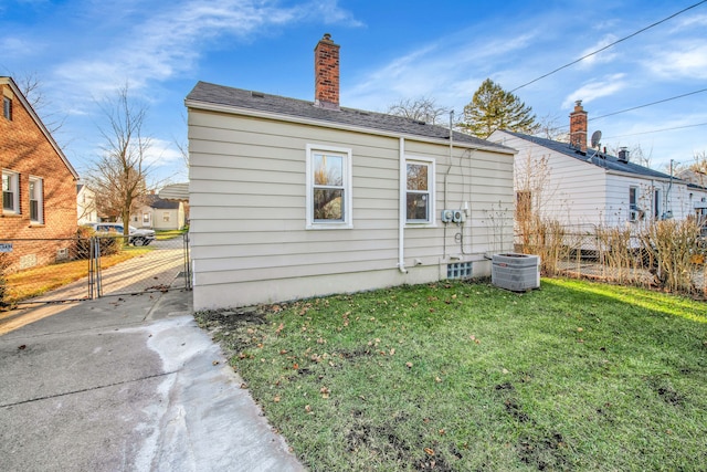 view of side of home featuring central AC unit and a lawn