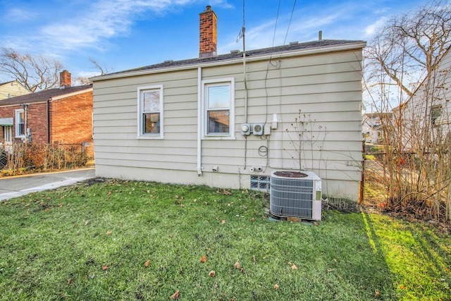 view of side of property with a yard and central AC