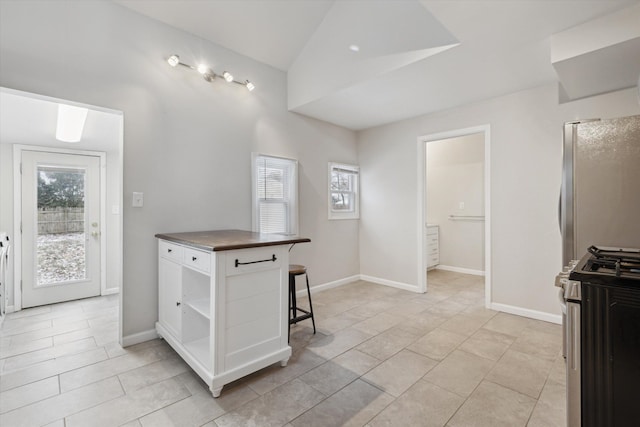 kitchen featuring a breakfast bar, stainless steel appliances, a kitchen island, white cabinetry, and light tile patterned flooring