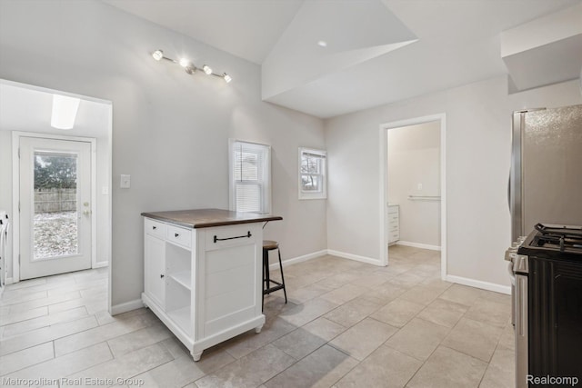 1597 W Saratoga St, Ferndale, MI 48220 - kitchen with stainless steel appliances, open shelves, white cabinetry, light tile patterned flooring, and lofted ceiling