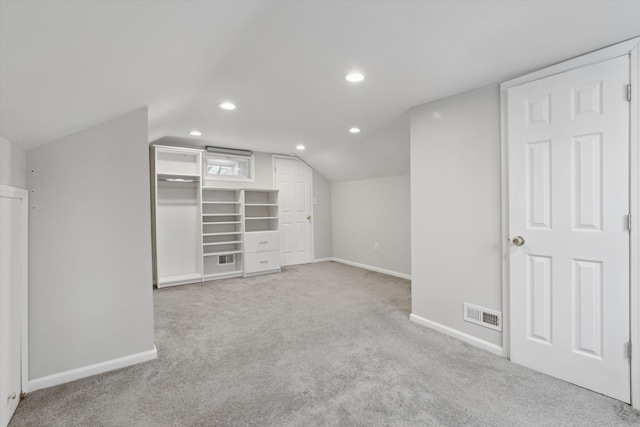 additional living space with light colored carpet and vaulted ceiling