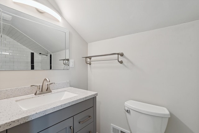 bathroom featuring vanity, toilet, and lofted ceiling