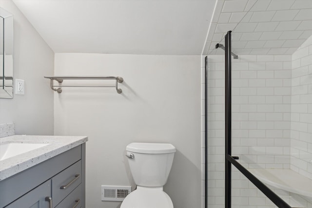 bathroom featuring a tile shower, vanity, and toilet