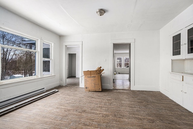 empty room with dark wood-type flooring and a baseboard radiator