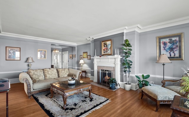 living area featuring baseboards, ornamental molding, wood finished floors, and a tile fireplace