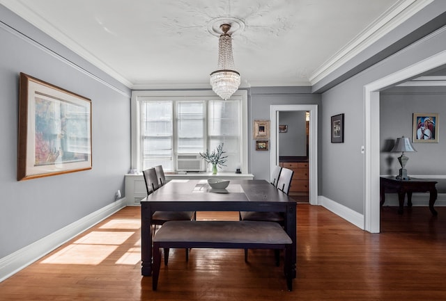 dining space with ornamental molding, a notable chandelier, and wood finished floors