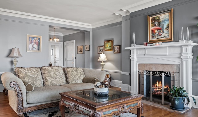 living area with crown molding, a fireplace, a chandelier, and wood finished floors