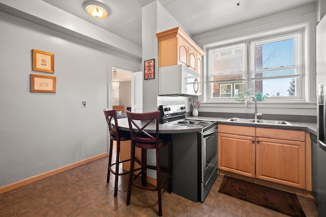 kitchen featuring white microwave, a sink, baseboards, stainless steel electric range oven, and dark countertops