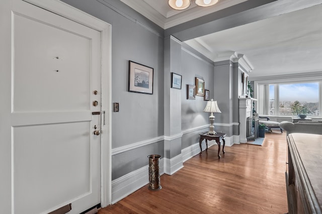 foyer entrance featuring baseboards, crown molding, and wood finished floors