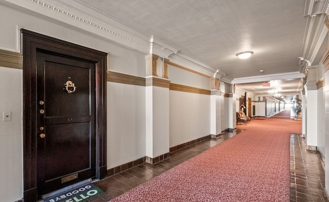 hall with baseboards, decorative columns, and crown molding