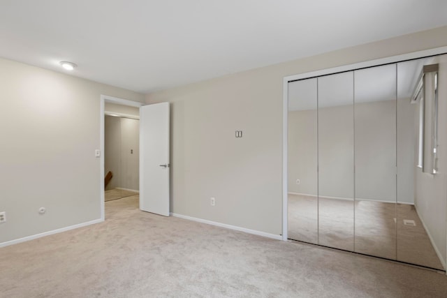 unfurnished bedroom featuring light colored carpet and a closet