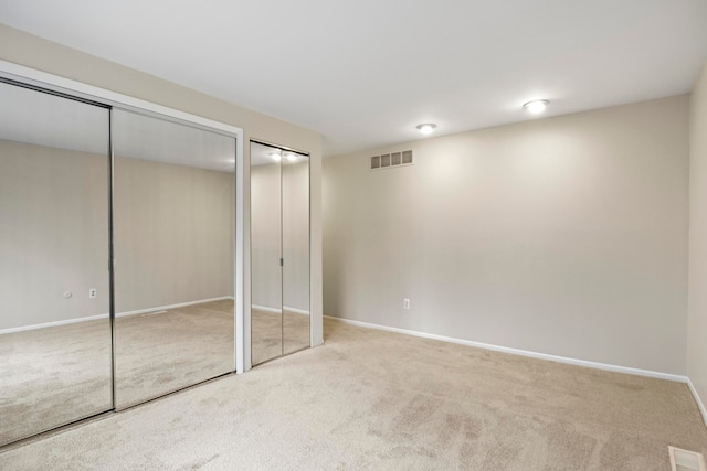 unfurnished bedroom with multiple closets and light carpet