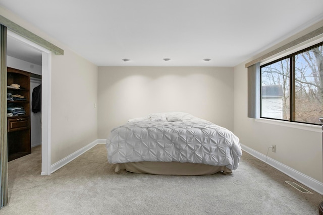 bedroom with light colored carpet, a spacious closet, and a closet