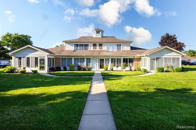 view of front of home with a sunroom and a front lawn