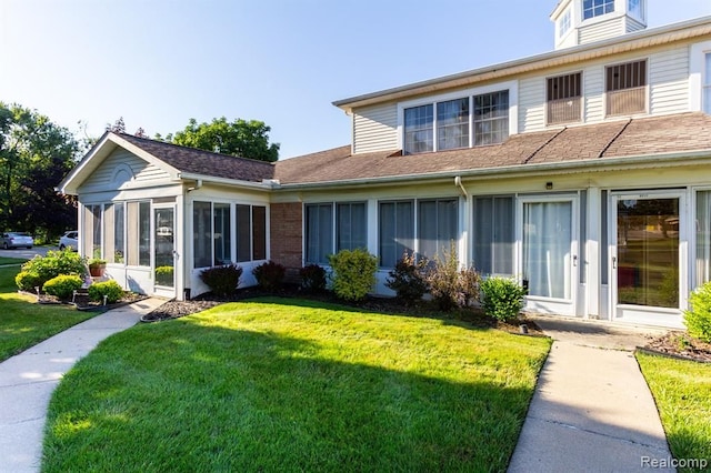 back of property with a sunroom and a yard