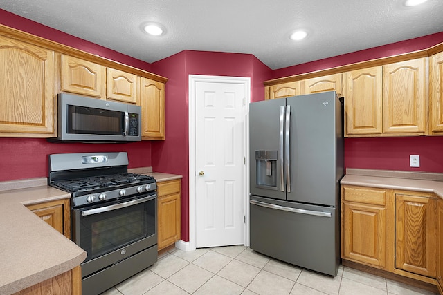 kitchen featuring light tile patterned floors, stainless steel appliances, and a textured ceiling