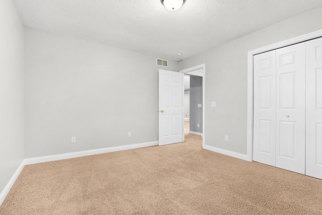 unfurnished bedroom featuring carpet flooring, a textured ceiling, and a closet