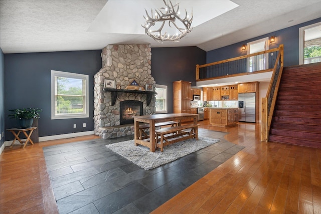 dining room featuring a textured ceiling, dark hardwood / wood-style flooring, a fireplace, and vaulted ceiling