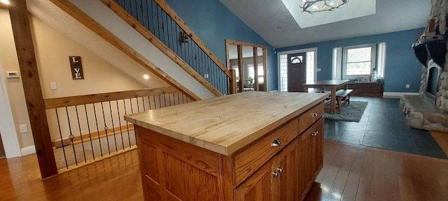 kitchen featuring wood counters, dark hardwood / wood-style flooring, a center island, and vaulted ceiling with skylight