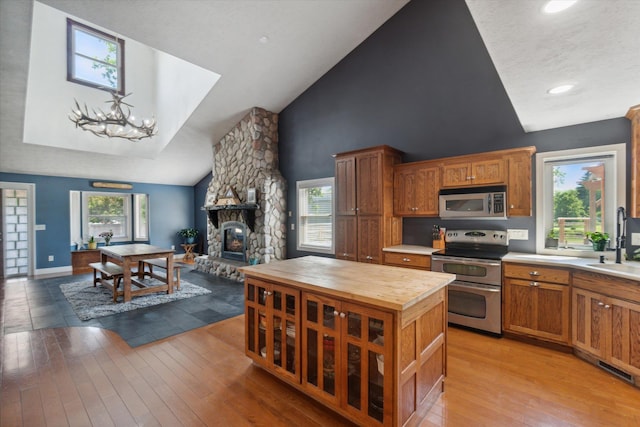 kitchen featuring light wood-type flooring, stainless steel appliances, sink, an inviting chandelier, and a fireplace