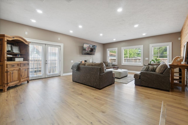 living room with light hardwood / wood-style floors, a textured ceiling, and french doors