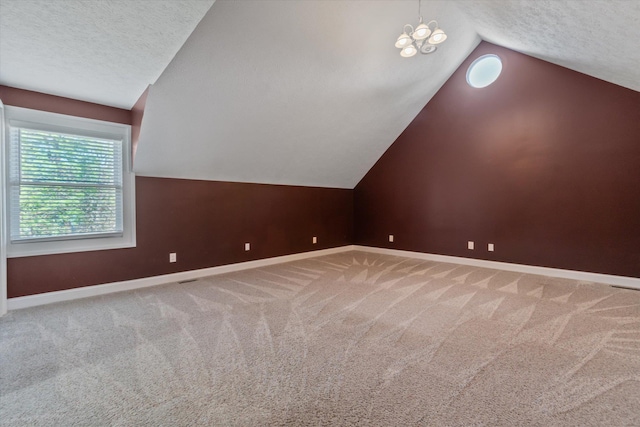 additional living space featuring a chandelier, a textured ceiling, carpet floors, and vaulted ceiling