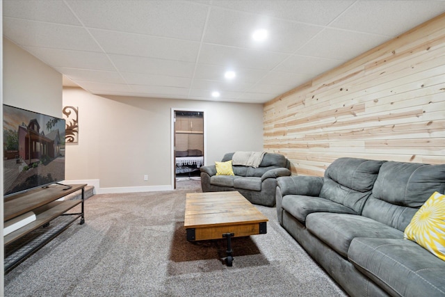 living room with a drop ceiling, carpet floors, and wooden walls