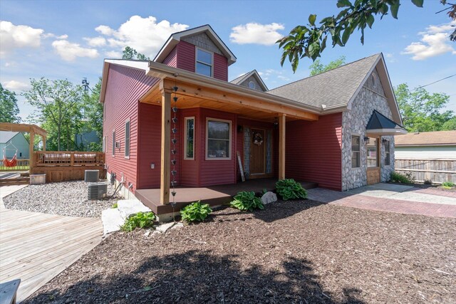 210 E Mcneil St, Corunna, MI 48817 - view of front of home featuring stone siding, fence, covered porch, and central AC unit