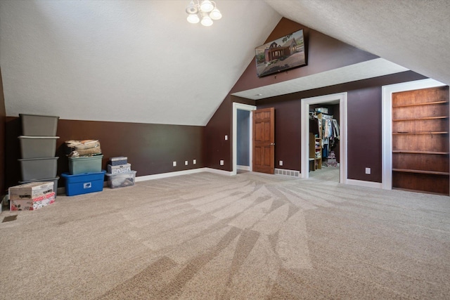 bonus room featuring vaulted ceiling, built in shelves, carpet floors, and a textured ceiling