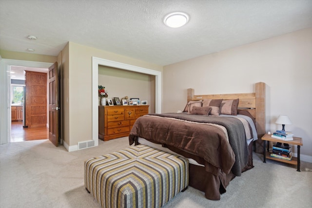 bedroom with a textured ceiling and light carpet