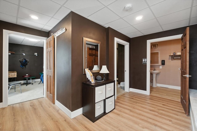 hallway with a barn door and light hardwood / wood-style flooring