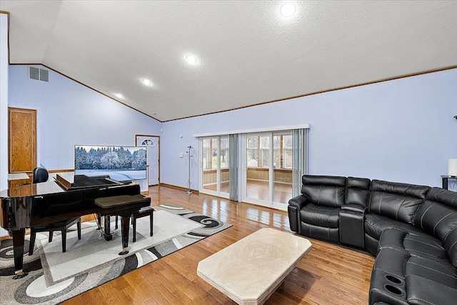 living room with a textured ceiling, crown molding, light hardwood / wood-style floors, and vaulted ceiling