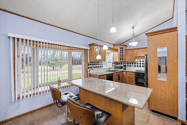 kitchen with black dishwasher, backsplash, stove, vaulted ceiling, and a kitchen bar