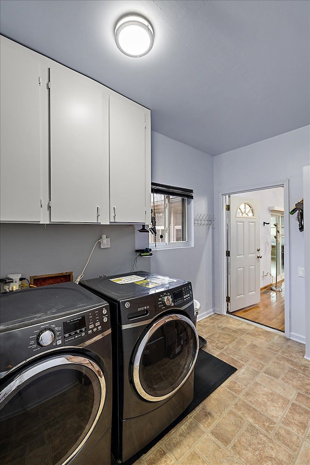 clothes washing area with cabinets and washer and clothes dryer