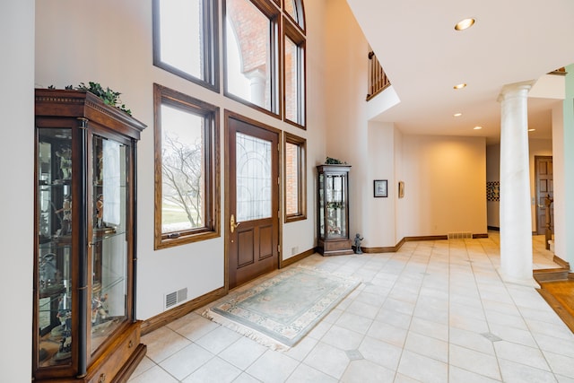 foyer with ornate columns, light tile patterned flooring, and a high ceiling