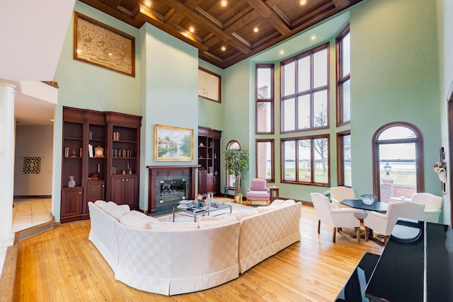 living room featuring a high ceiling, coffered ceiling, light wood-type flooring, beamed ceiling, and wood ceiling