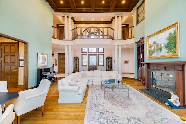 living room with light hardwood / wood-style floors, a high ceiling, and decorative columns