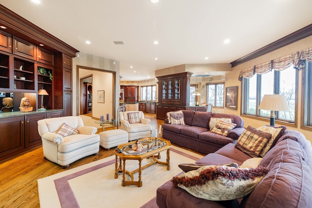 living room with ornamental molding and light hardwood / wood-style flooring