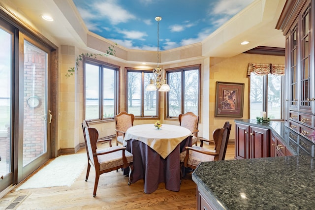 dining area featuring light hardwood / wood-style floors, ornamental molding, and an inviting chandelier