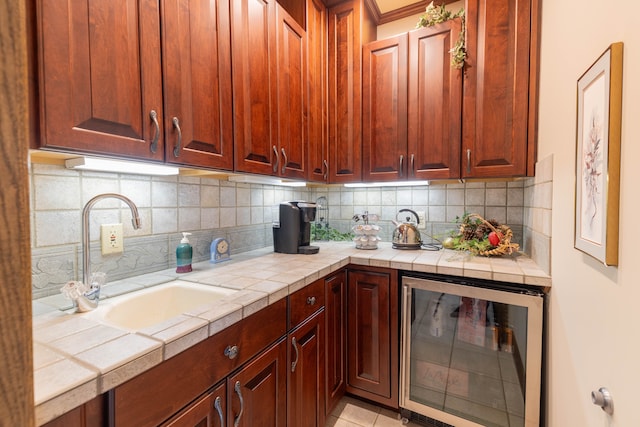 kitchen featuring sink, beverage cooler, backsplash, tile countertops, and light tile patterned flooring